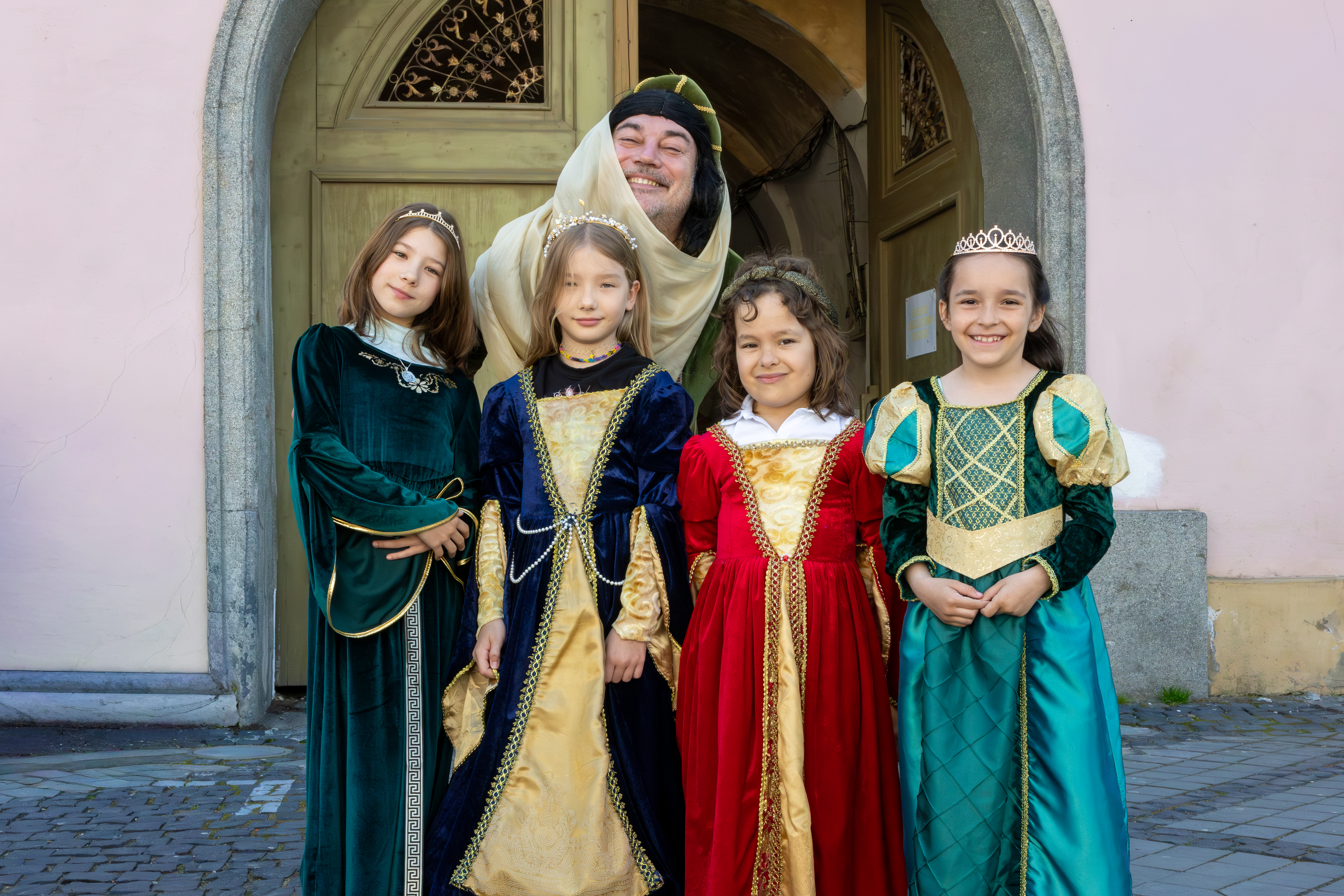 4 fillettes vêtues de tenue médiévale : 4 petites princesses médiévales au premier plan. Elles se trouve sur une rue de Sibiu. Derrière elles, se trouve un homme, vêtu lui aussi en tenues médiévales de femme. Il voulait lui aussi laisser l’impression qu’il fait partie des princesses.