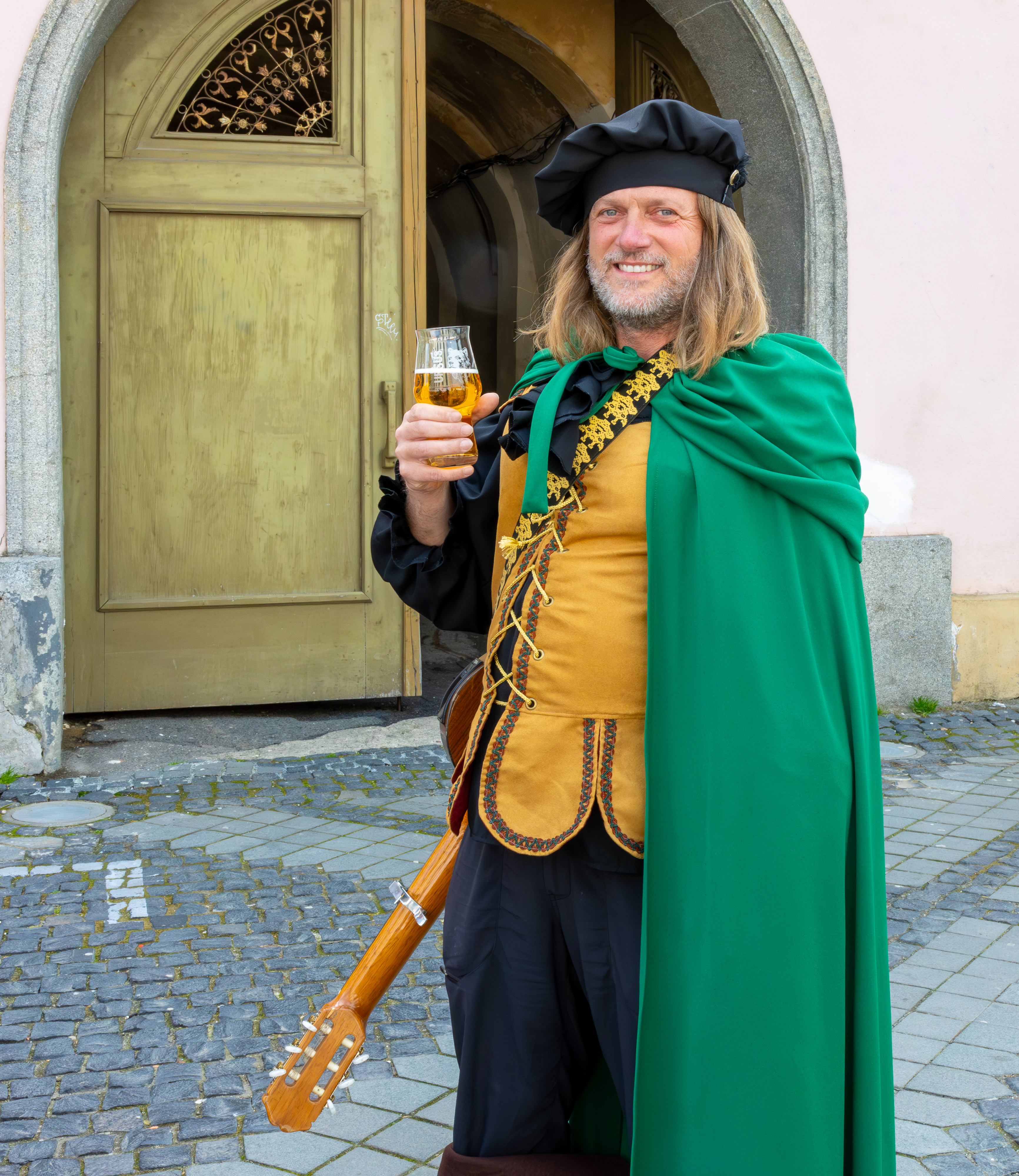 Un troubadour devant une boutique de la Grande Place de Sibiu, un verre de bière à la main.