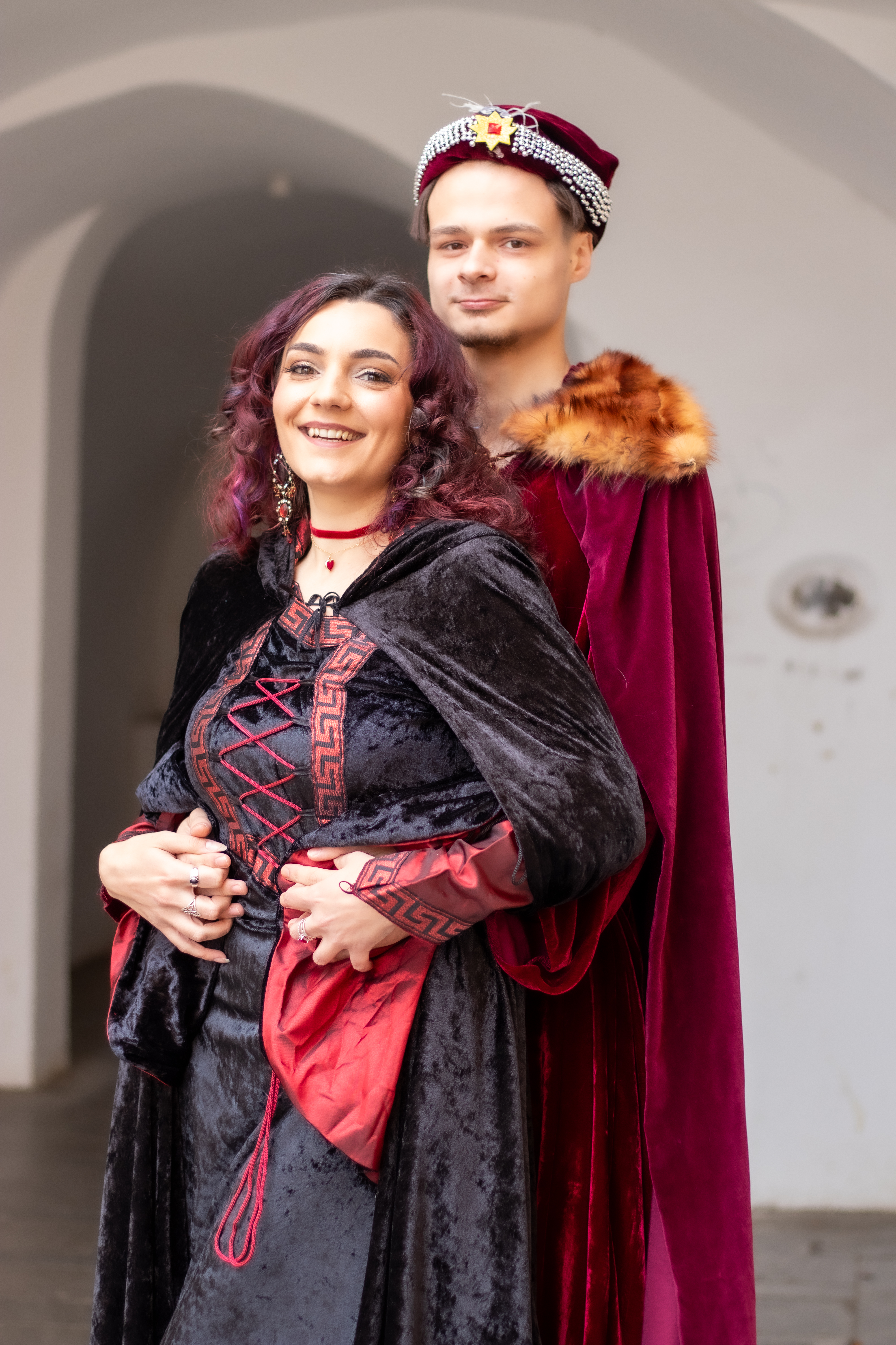 Jeune couple vêtu de tenues médiévales au premier plan. En arrière-plan une arche de Sibiu.