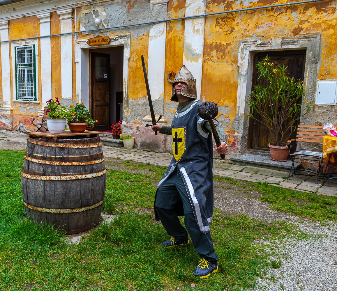 Scène de reconstitution historique avec un personnage costumé en chevalier dans la cour d'un palais médiéval de Transylvanie.